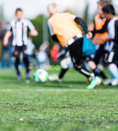 football match playing in distance, close up of football pitch turf