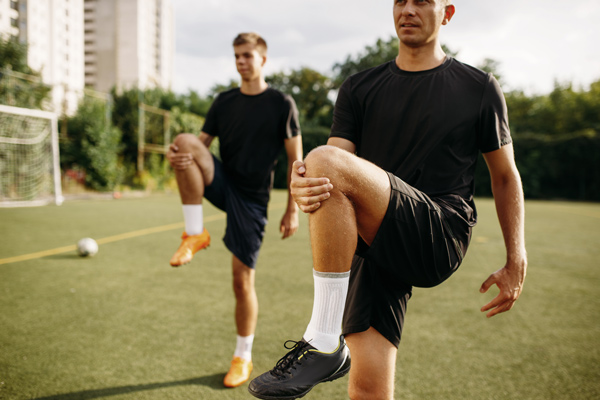 team training, footballers stretching leg muscles into chest