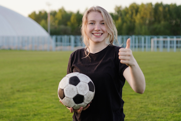 young happy girl holding football and giving a thumbs up