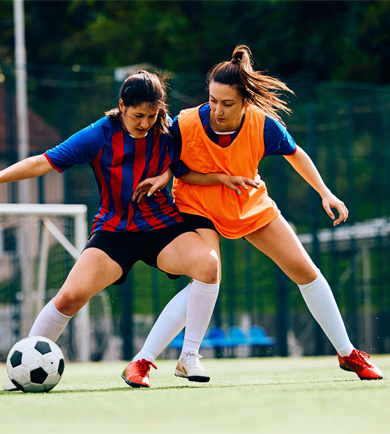 two female football players tackling ball